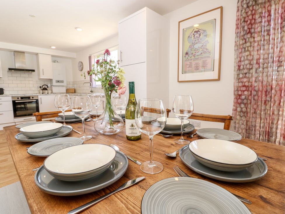 A dining table set with plates glasses a bottle of wine and flowers in a kitchen at Cava in Seaview