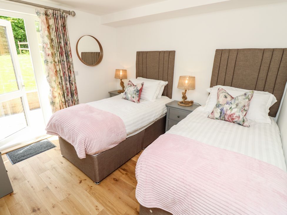A bedroom with two single beds with pink throws and floral cushions at Cava in Seaview