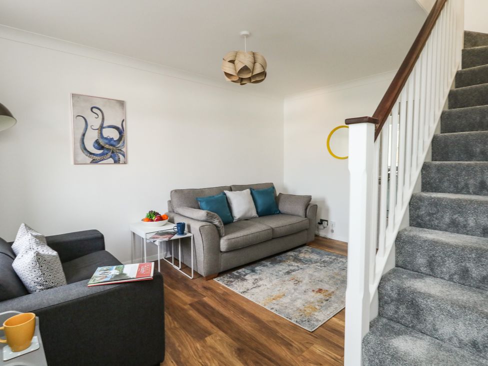 A living room with two sofas a small table with fruit a rug and carpeted stairs at Little Tern Brewers Quay Harbour