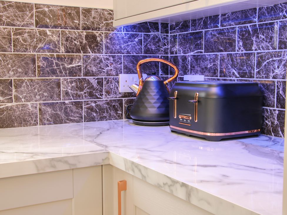 A kitchen countertop with a black kettle and black toaster against a dark marbled tile backsplash at Holly Lodge in Forden near Montgomery