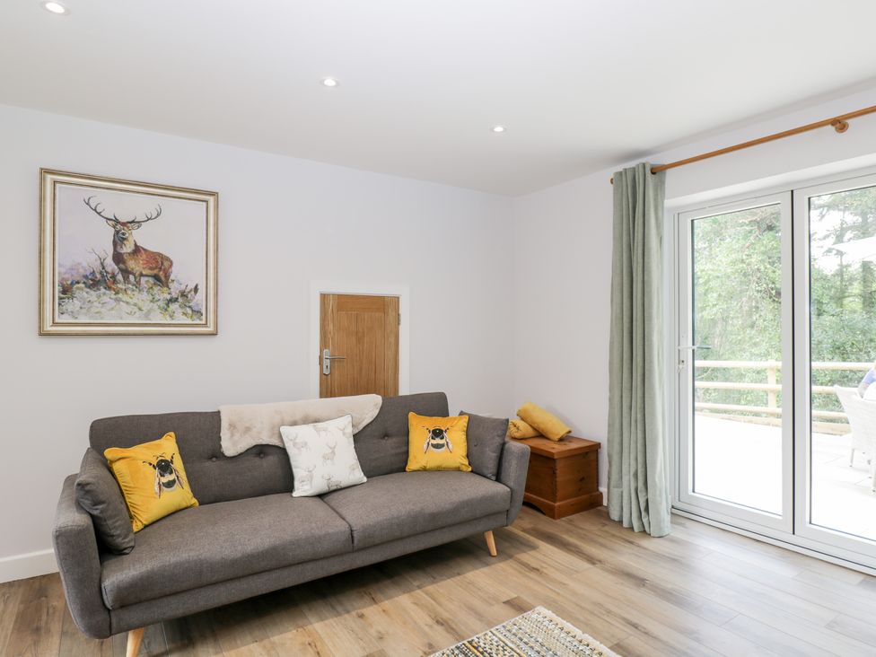 A living room with a gray sofa with cushions and a small wooden door on the wall at Stag Cottage in Lytchett Matravers