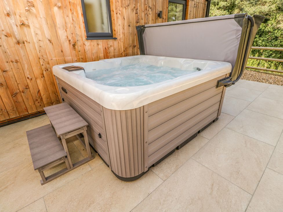 An outdoor hot tub with steps beside a wooden wall at Stag Cottage in Lytchett Matravers