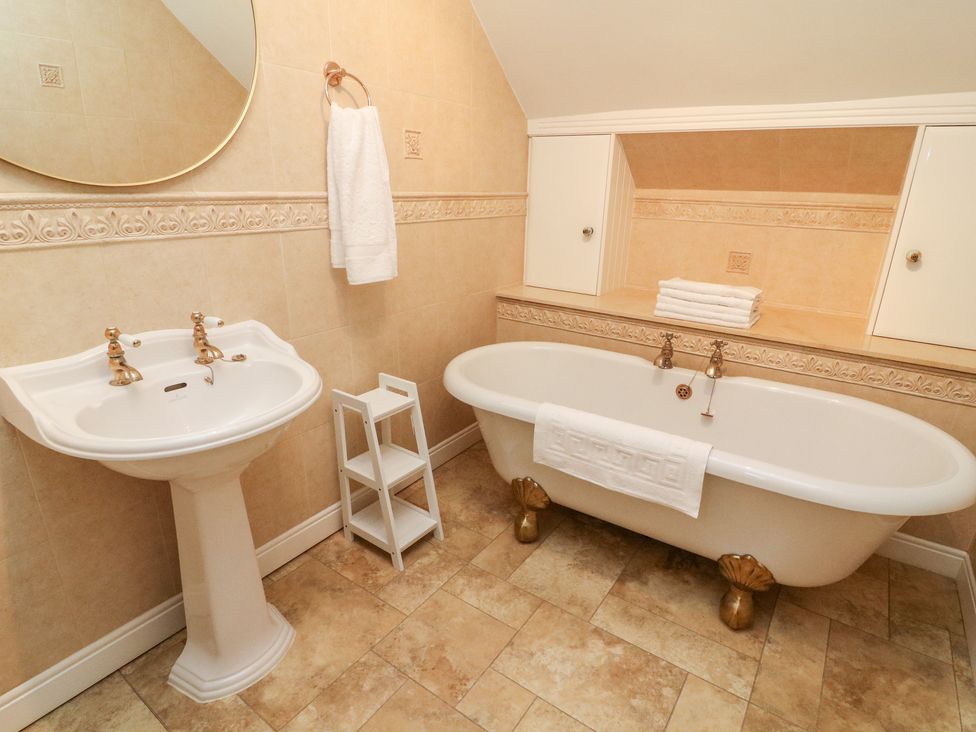 A bathroom with a pedestal sink and a clawfoot bathtub with towels at Heanor House in Leyburn