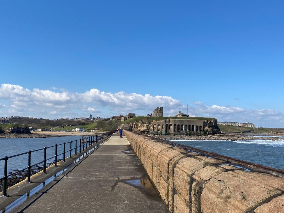 A stone pier with metal railings leading to historic ruins by the sea at Studio 51 @ Tynemouth