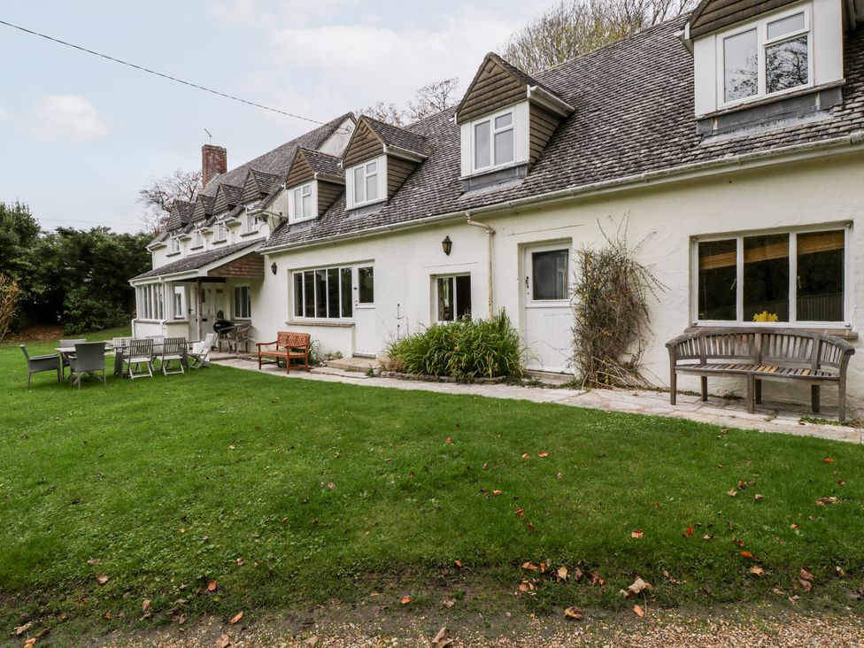 A garden with chairs benches and tables outside a white house with dormer windows at The Studio - Arne in Arne near Stoborough