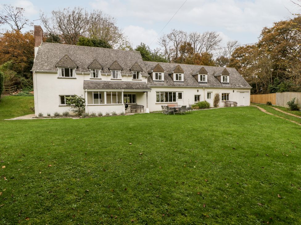 A large white house with multiple dormer windows and a grassy lawn with outdoor table and chairs at The Studio - Arne in Arne near Stoborough