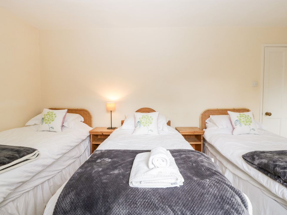 A bedroom with three single beds each with white bedding and floral pillows at The Studio - Arne in Arne near Stoborough
