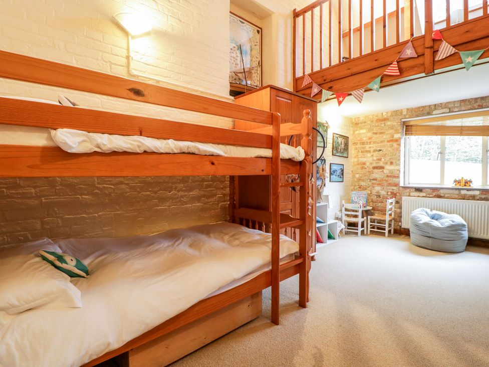 A bedroom with wooden bunk beds a small table and chairs bean bag and window at The Studio - Arne in Arne near Stoborough