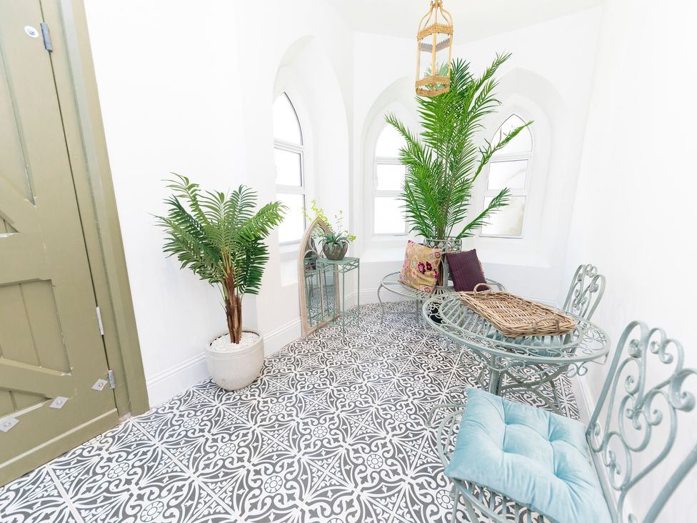 A room with patterned tile floor metal chairs and table plants and an arched mirror at Bishops Retreat in Ventnor