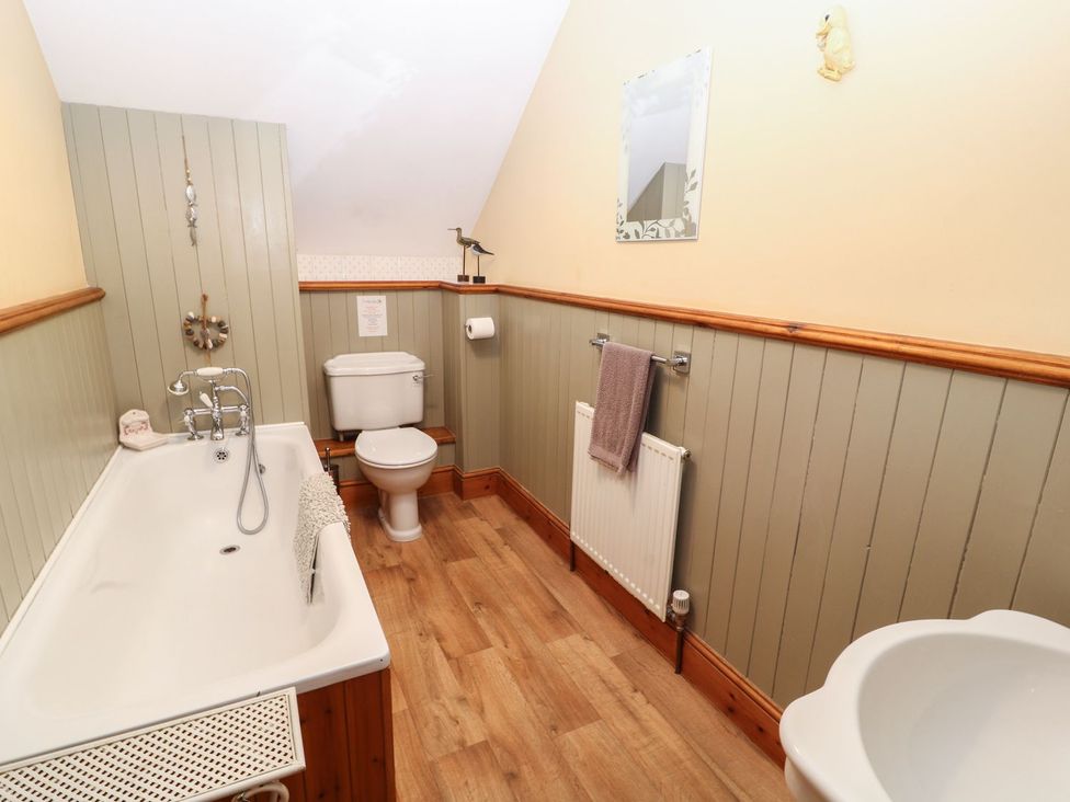 A bathroom with a bathtub toilet sink mirror and towel at Hazel Barn in North Molton