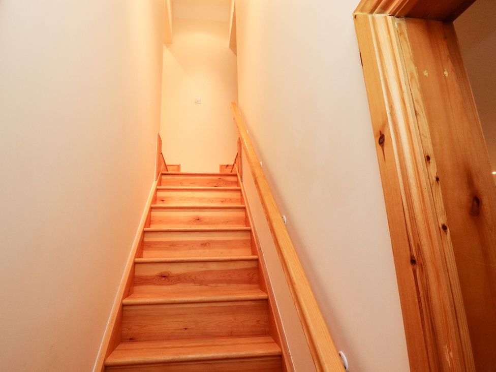 A wooden staircase with a handrail and wooden doorframe at The Old Dairy, Ellerby in Runswick Bay