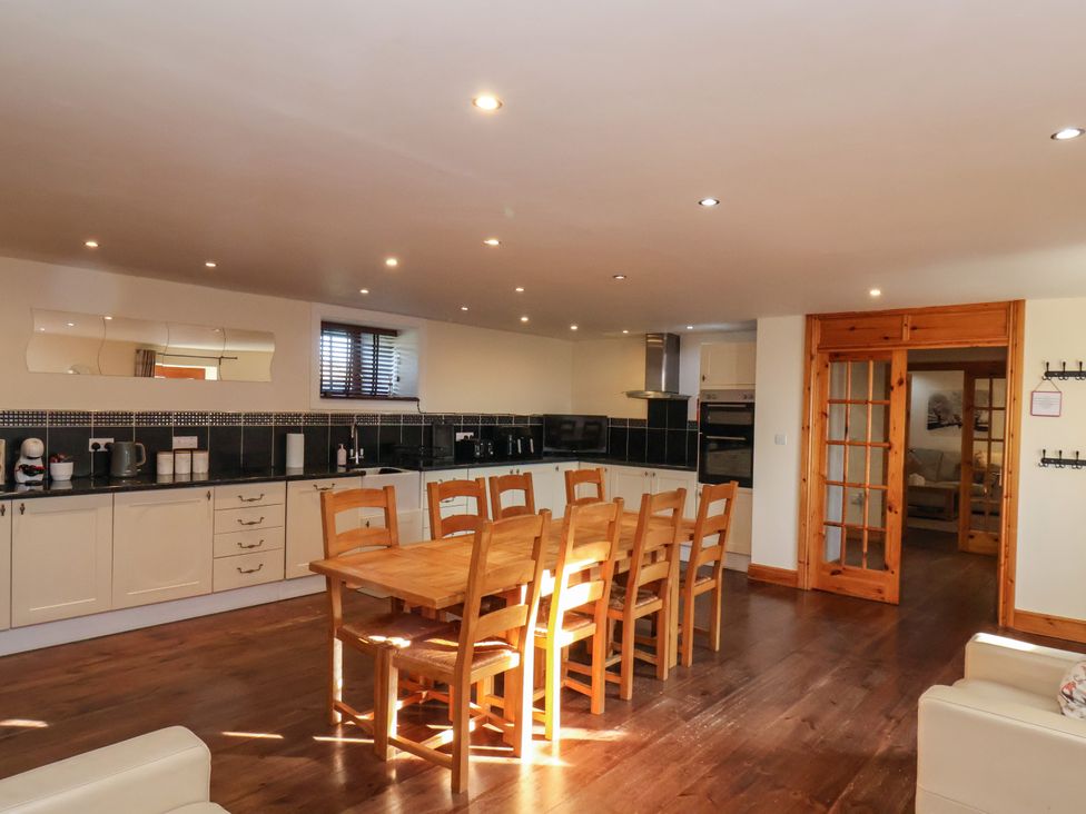 A kitchen with a wooden dining table and chairs and cabinets with appliances at The Old Dairy Ellerby in Runswick Bay