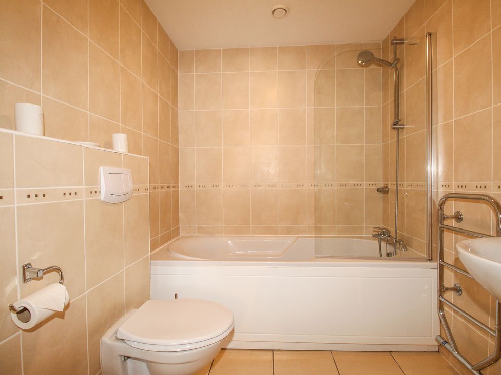 A bathroom with a bathtub shower toilet and sink at Broadleys in Swanage