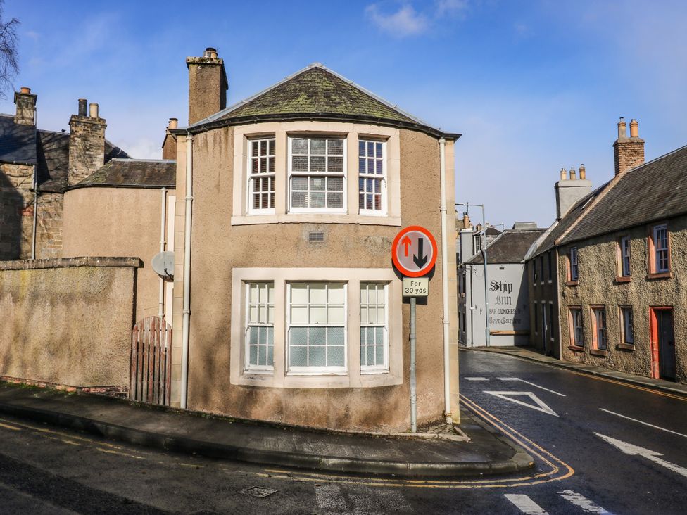 A street corner with beige buildings and a traffic sign showing priority for oncoming vehicles at The Toll House in Melrose