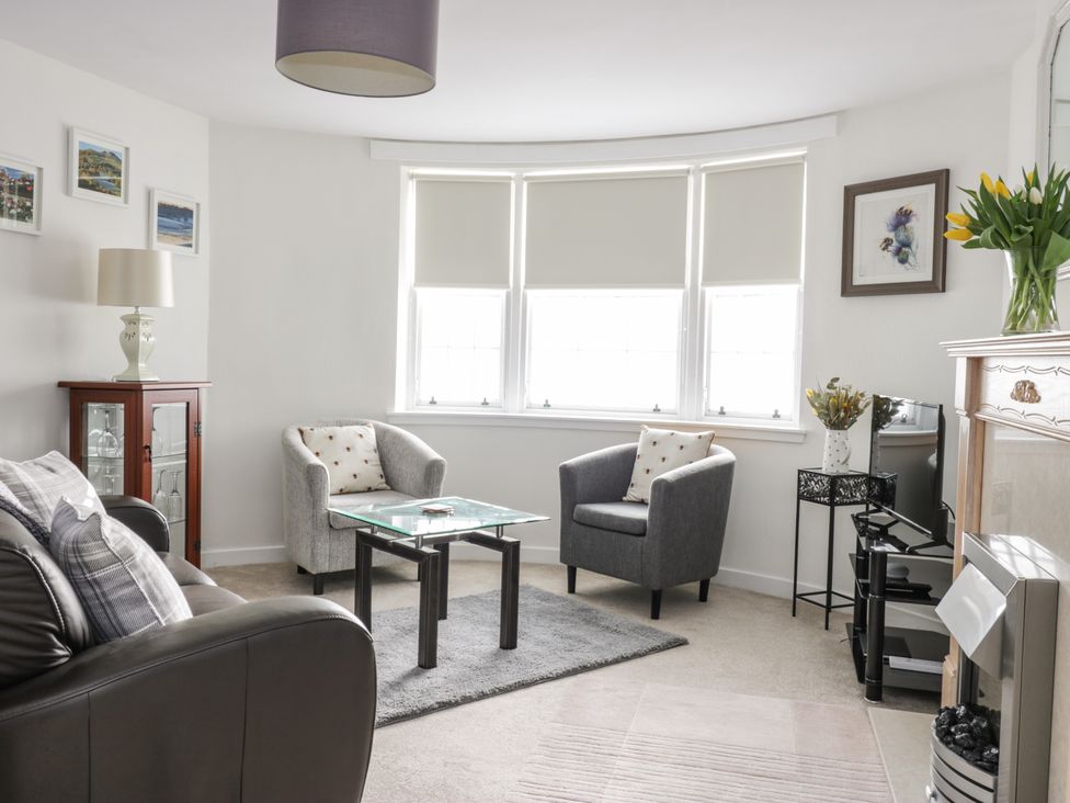 A living room with armchairs a sofa a glass coffee table and a TV at The Toll House in Melrose