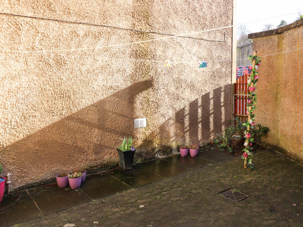 A small outdoor patio area with a textured wall several plant pots and a clothesline at The Toll House in Melrose