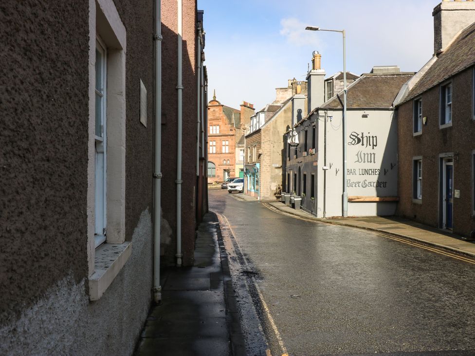 A narrow street with buildings and a sign for Ship Inn on a sunny day at The Toll House in Melrose