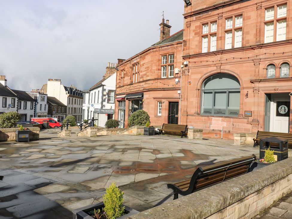 A town square with benches and planters near red brick and white buildings at The Toll House in Melrose