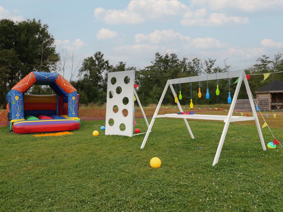 An outdoor area with a colorful bouncy castle white game boards and inflatable bowling pins at Lodge 7 - The Earn in Errol