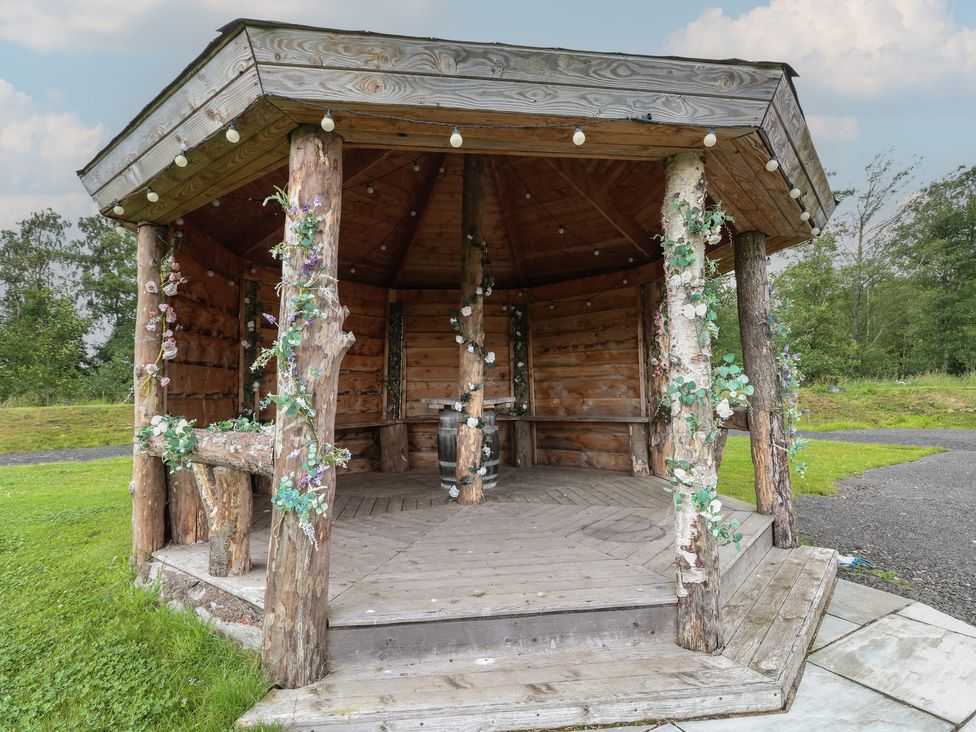 A wooden gazebo with floral decorations on the posts and string lights at Lodge 7 - The Earn in Errol