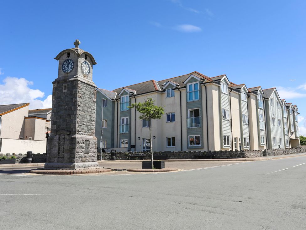 A street corner with a stone clock tower a small tree and a residential building at 3 Tai Newydd in Llanfaelog near Rhosneigr