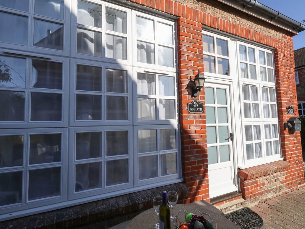 An exterior view of a brick building with white framed windows and door a table with a bottle of wine and glasses in front at Goliath Brewers Quay Harbour