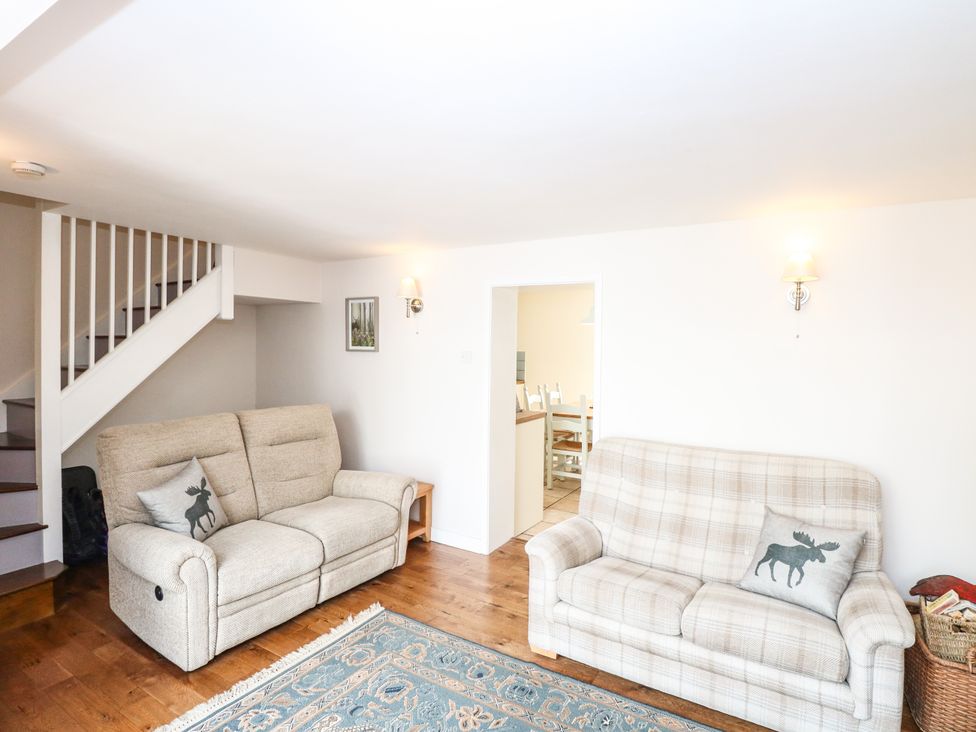 A living room with two sofas and a staircase at 1 Chelsea Cottage in North Elmham