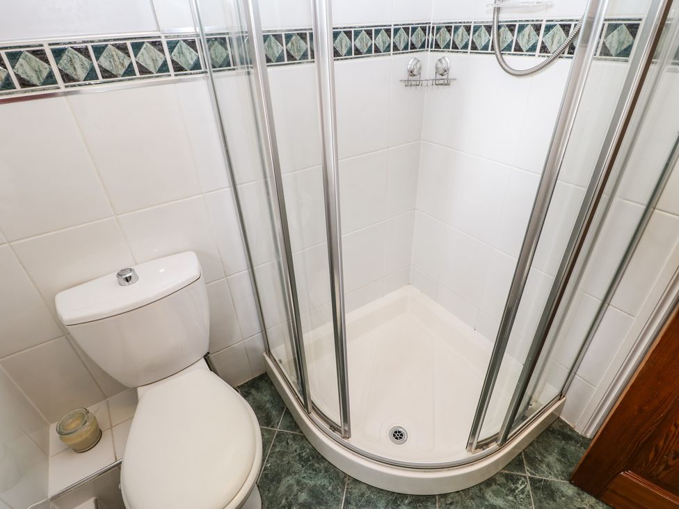 A bathroom with a toilet and a corner shower enclosure at Pine Cottage Appleby-In-Westmorland