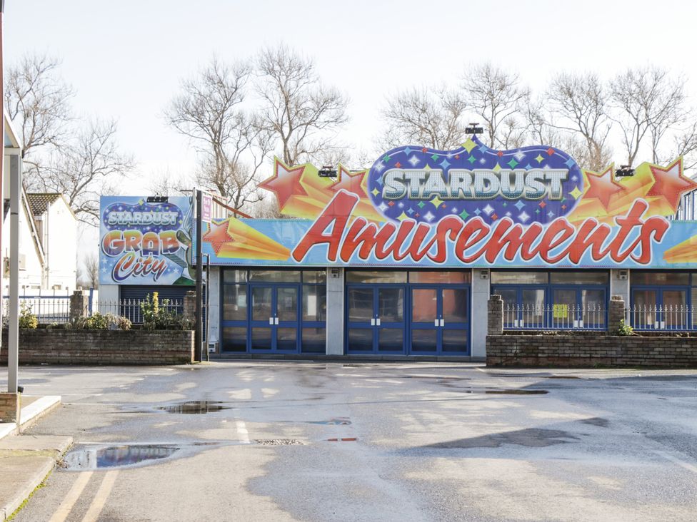 A closed amusement arcade building with Stardust Amusements sign and empty wet parking area at Little Walton in Burnham-On-Sea