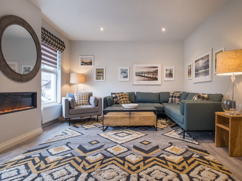 A living room with a sectional sofa armchair coffee table and wall art at Howe Keld 5 First Floor in Keswick