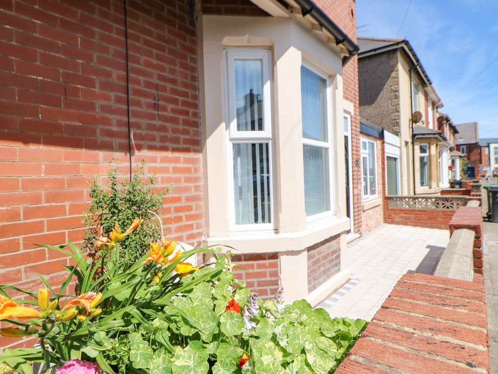 A front porch with tiled floor and a flower bed outside a brick house at Lobster Pot Retreat in Newbiggin-By-The-Sea