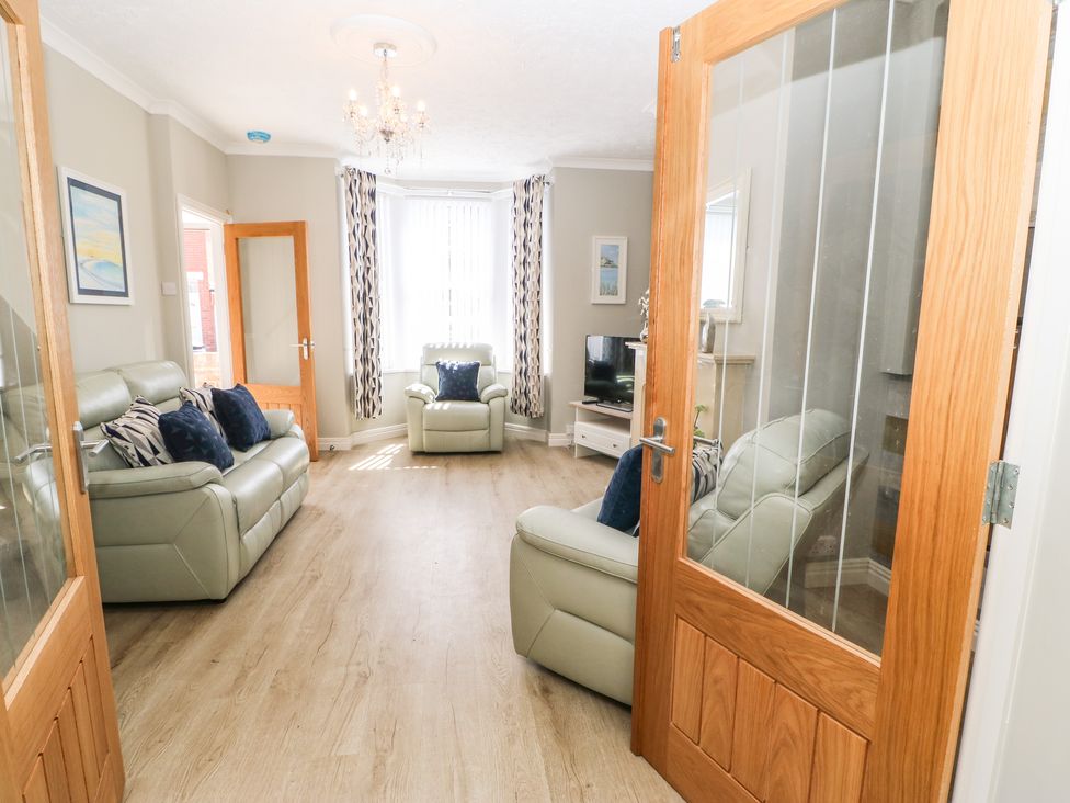 A living room with leather sofas wooden flooring and a television at Lobster Pot Retreat in Newbiggin-By-The-Sea