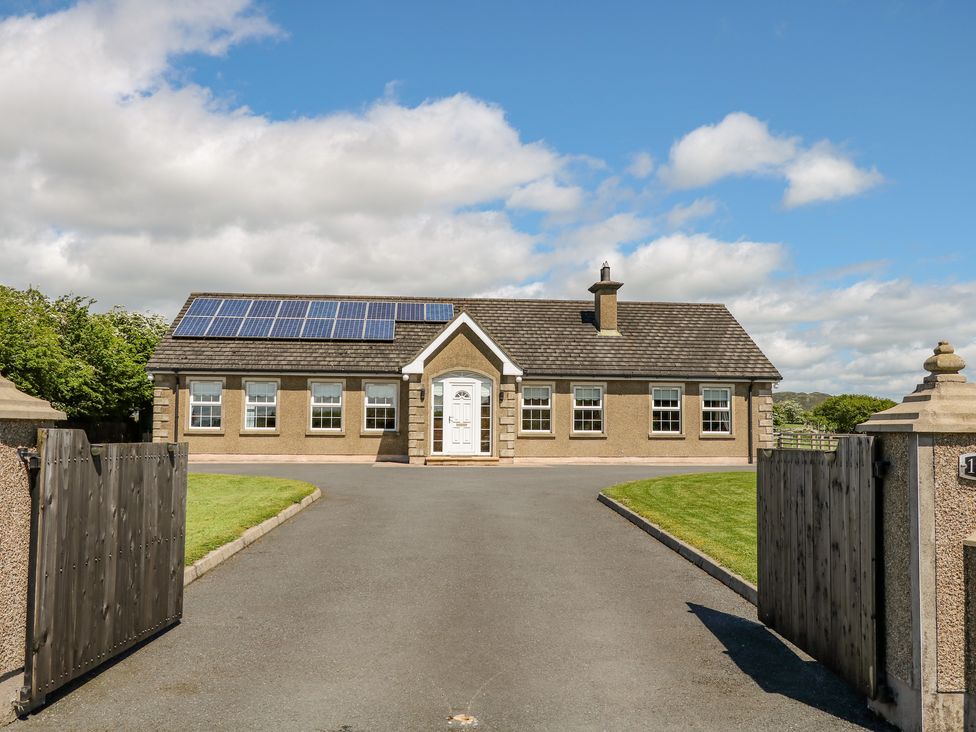 A single story house with solar panels on the roof a paved driveway and wooden gates at Willow Tree Farm House in Newry near Jonesborough