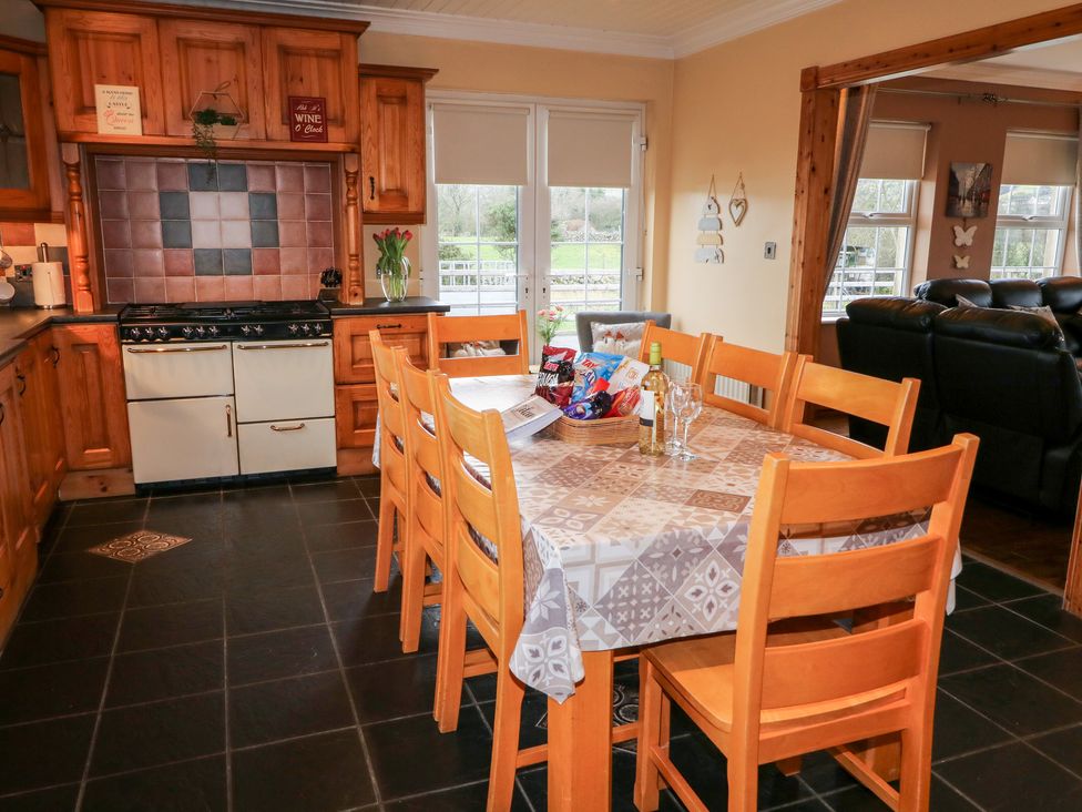 A kitchen with wooden cabinets a dining table with chairs and snacks on the table at Willow Tree Farm House in Newry near Jonesborough