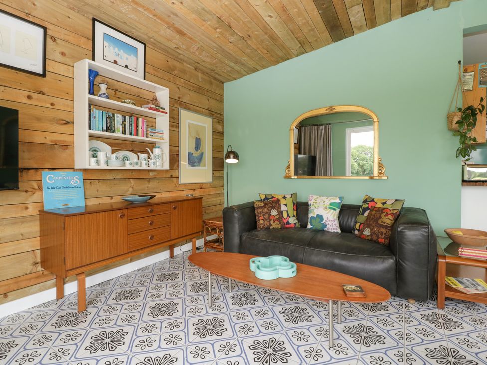 A living room with a black leather sofa cushions wooden coffee table and sideboard at Lulu Logs in Congresbury