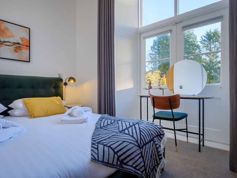 A bedroom with a bed pillow and towels and a chair by a window at The Margaret Suite Stone Cross Mansion in Ulverston