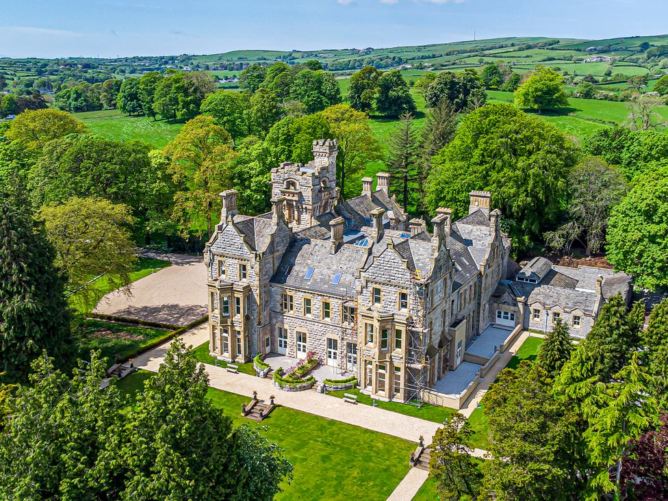 A large stone mansion surrounded by trees and green fields at The Violet Suite Stone Cross Mansion in Ulverston