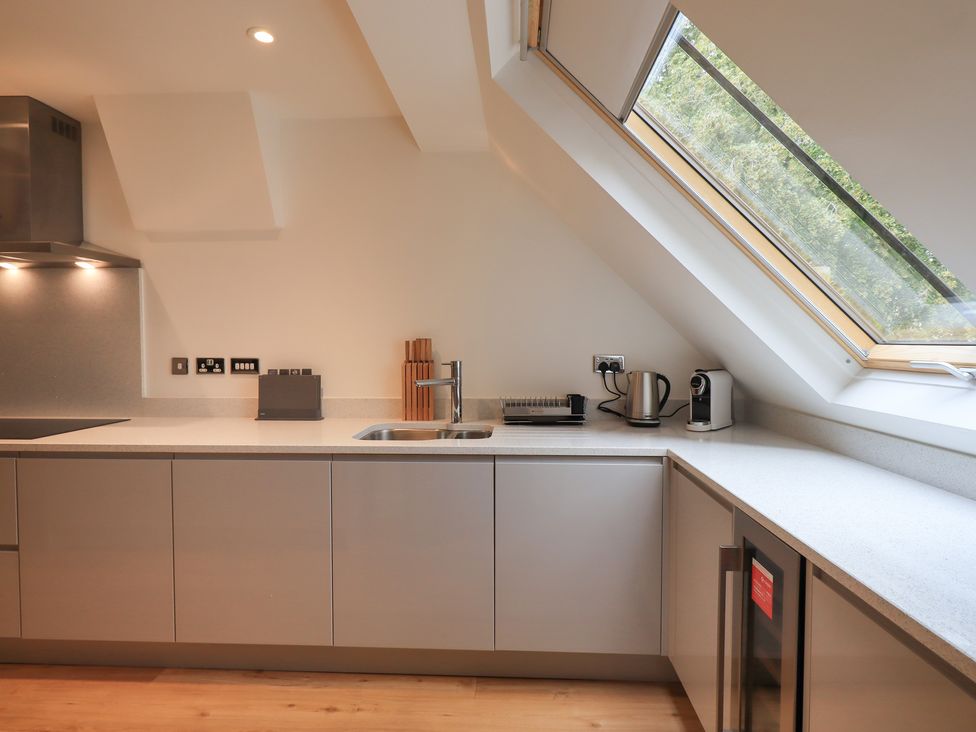 A kitchen with a sink kettle coffee machine knives and a slanted window at The Violet Suite Stone Cross Mansion in Ulverston