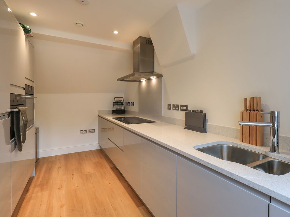 A kitchen with wooden floor and a countertop with sink stove and knives at The Violet Suite Stone Cross Mansion in Ulverston