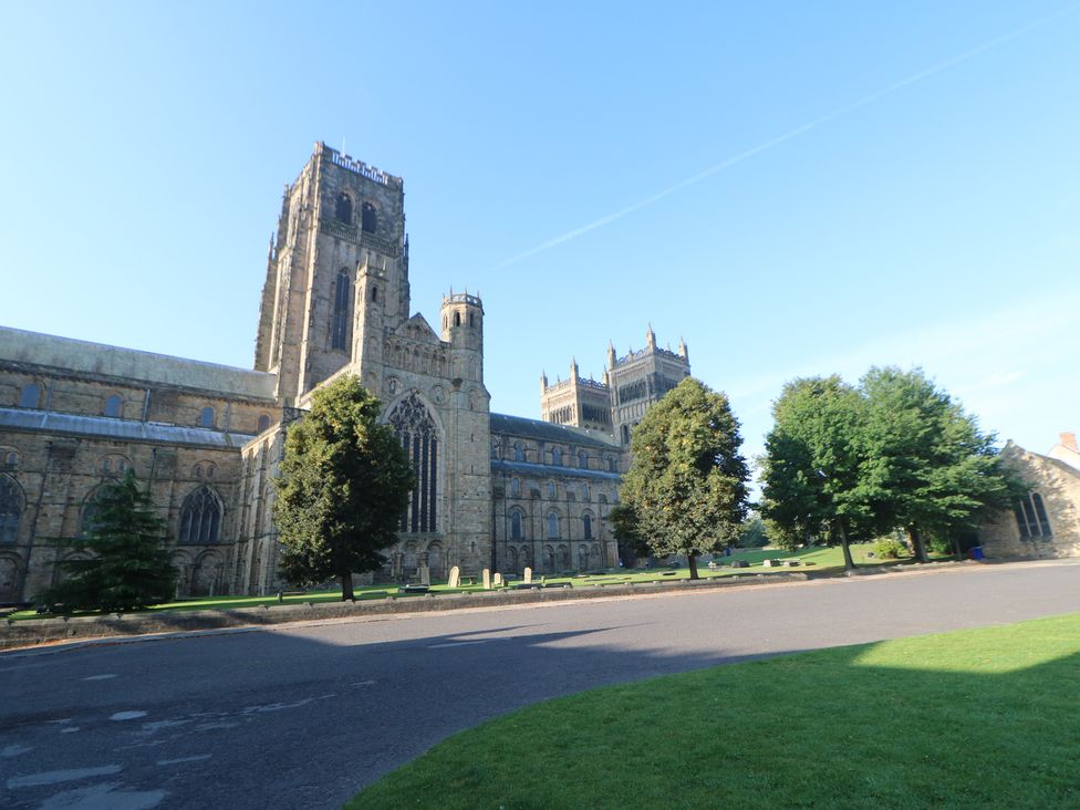 A large stone cathedral with towers surrounded by grass trees and a paved road at Dale Cottage in Ingleton County Durham