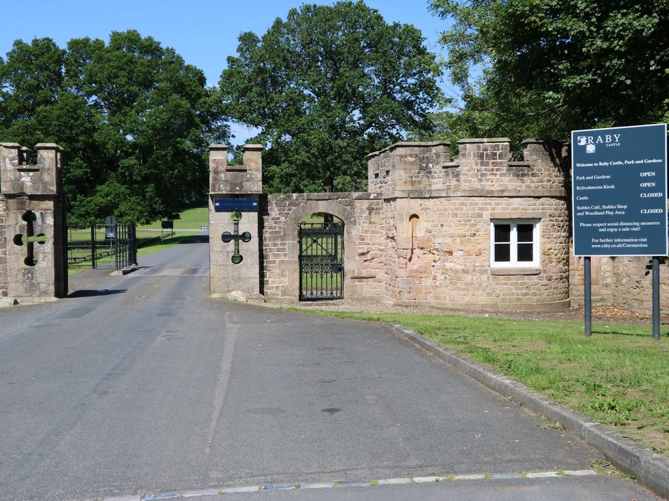 Entrance gate with stone walls and a sign at Raby Castle Ingleton County Durham