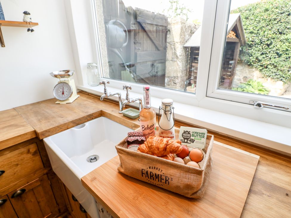A kitchen sink with a basket of groceries on wooden countertop at Dale Cottage in Ingleton County Durham