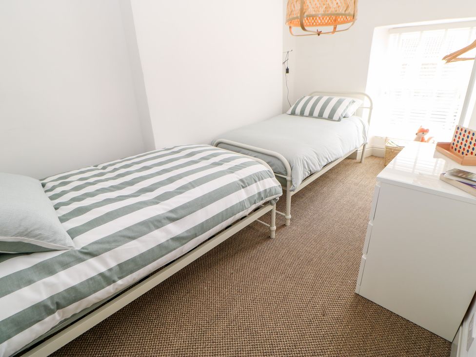 A bedroom with two single beds a white dresser and a window at Dale Cottage in Ingleton County Durham