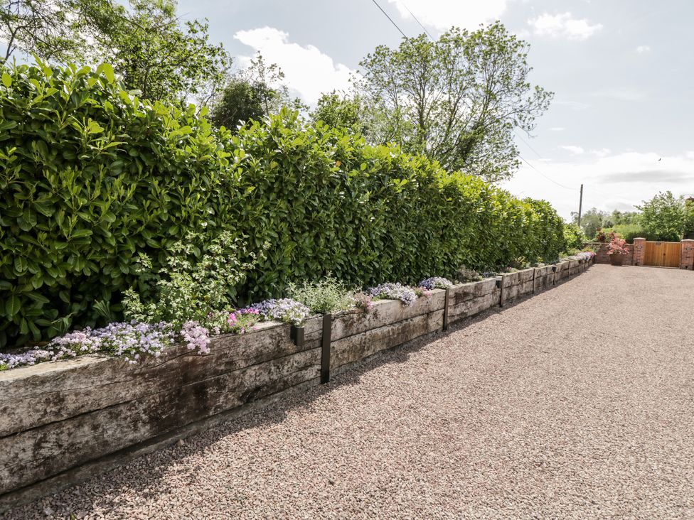 A gravel driveway with raised flower beds and a tall hedge at Little Lugg in Cross Keys near Hereford