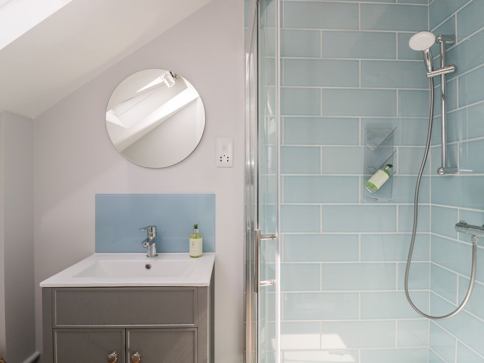 A bathroom with a sink cabinet mirror and a shower with blue tiles at Little Lugg in Cross Keys near Hereford