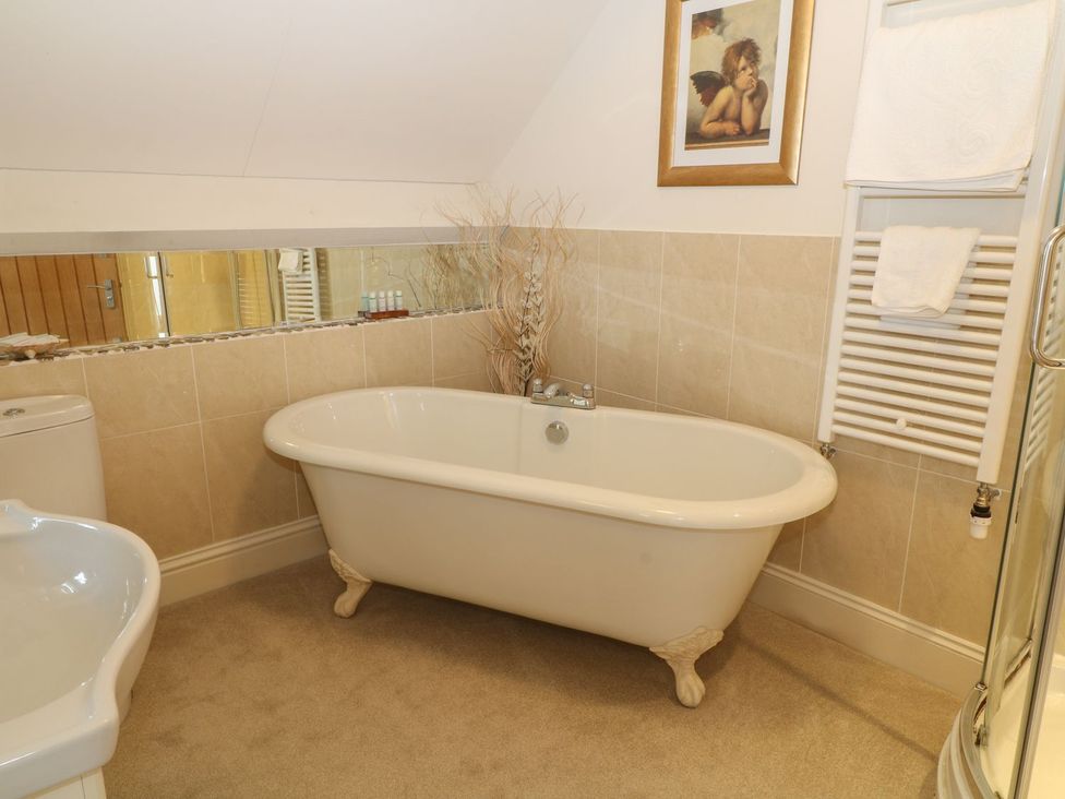 A bathroom with a clawfoot bathtub a toilet a sink a radiator with towels and a framed picture at Higher Weddicott Barn in Chagford