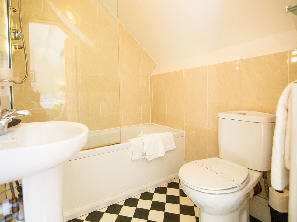 A bathroom with a sink toilet bathtub and checkered floor tiles at Higher Weddicott Barn in Chagford