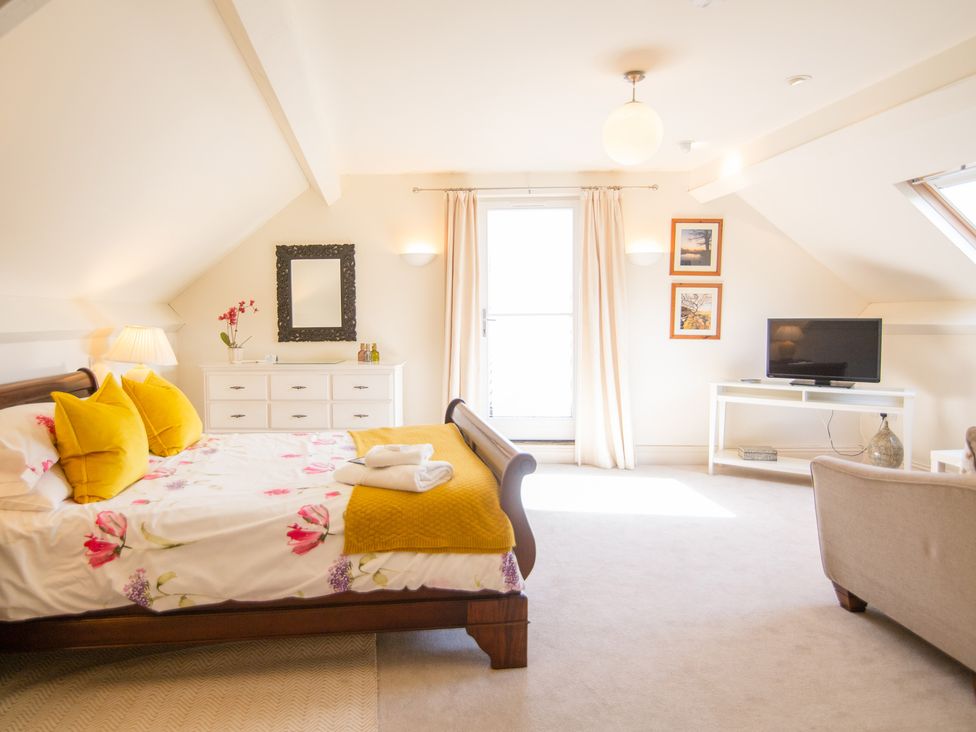 A bedroom with a wooden bed with floral bedding and yellow pillows at Higher Weddicott Barn in Chagford