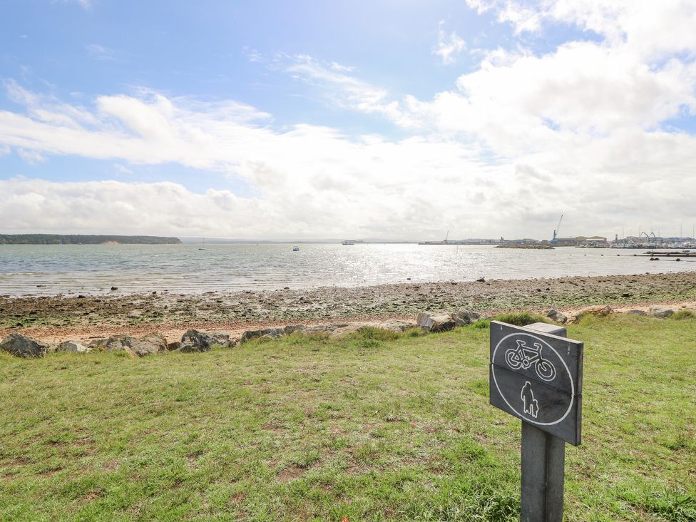 A beach view with grassy area rocks and a sign showing no bicycles or dogs at Poole Quay Cottage in Poole