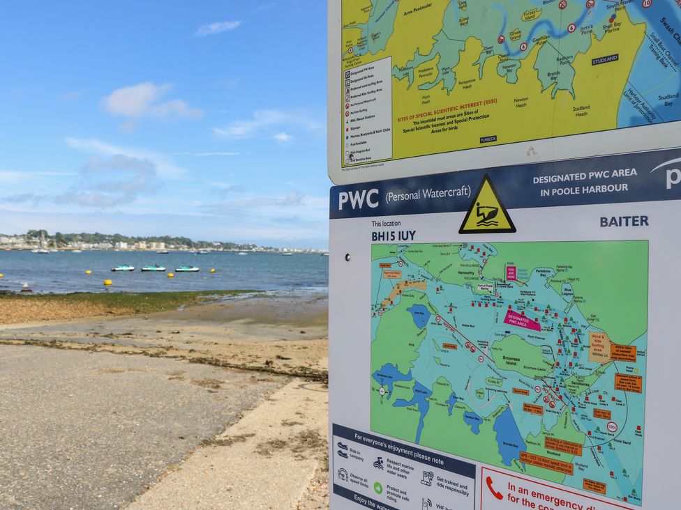 A map and information sign for personal watercraft at a beach with water and distant shoreline in Poole